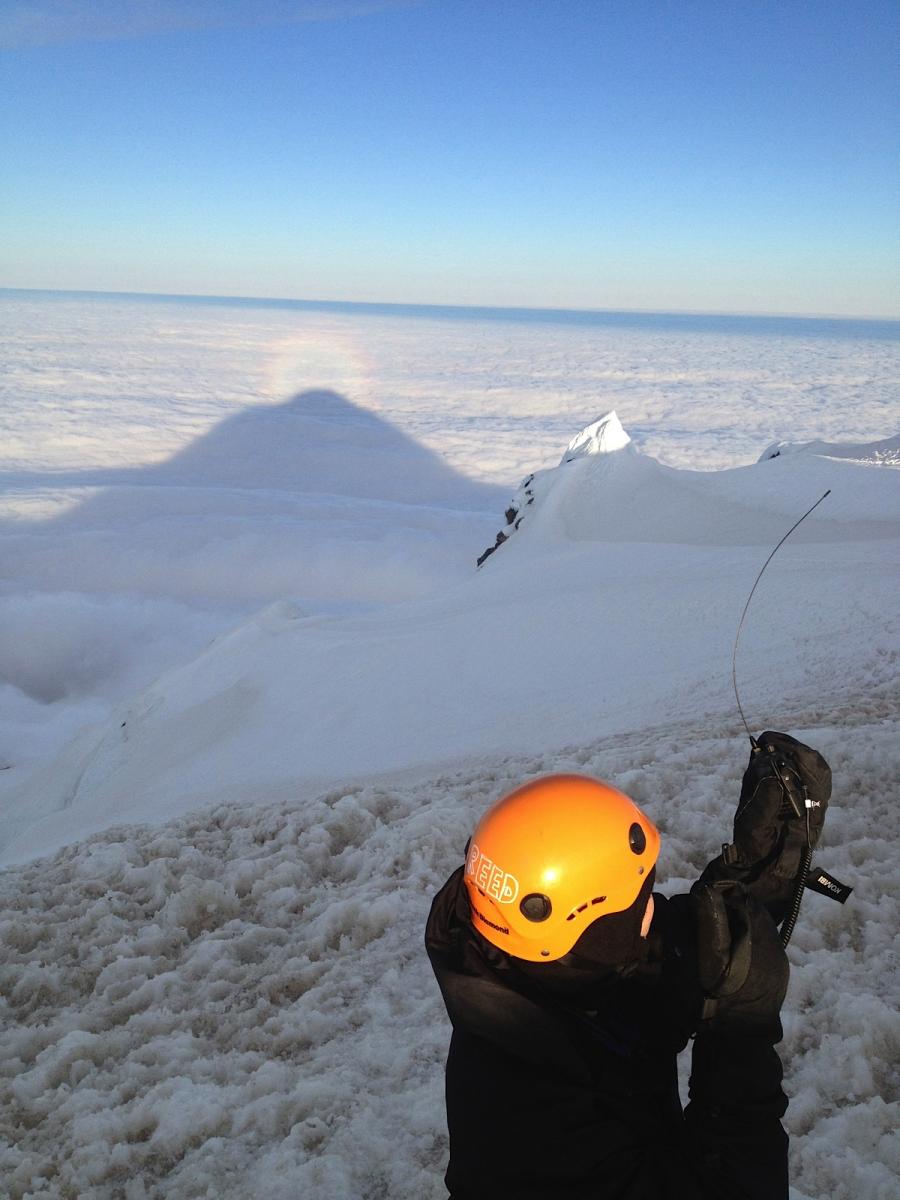 Rodney's photo of KB3QEW operating with Yaesu VX-8GR on Mount Hood summit in the sun looking west