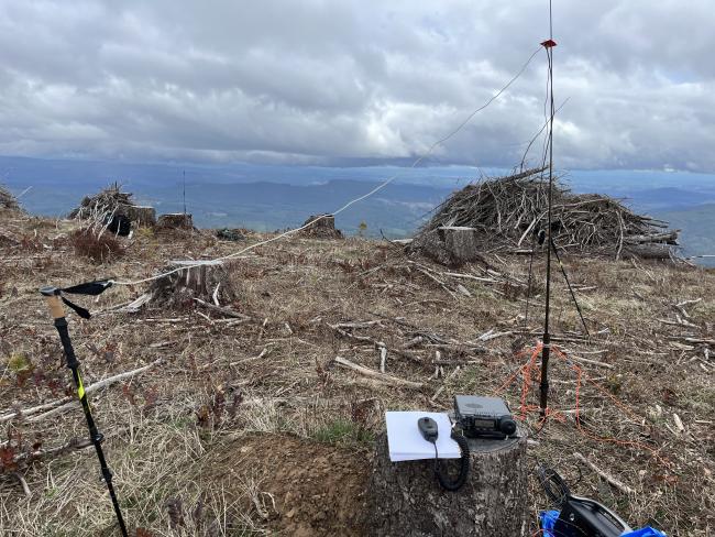 FT-857D radio sitting on a stump with wire dipole antenna set up behind