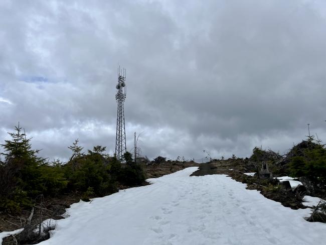 Snowy trail showing peak with gate at the top and radio tower on peak