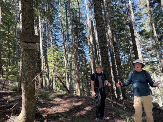 2 guys by an unmaintained trail sign
