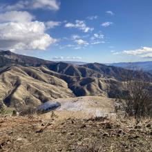A nearby ridge with clouds and other mountains in the background